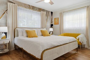 A bedroom with a bed, bedside tables, a chair, and curtains. - Poolside Retreat Sleeps 8 Putt Putt Hot Tub (Bradenton)