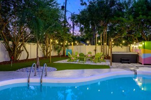 Una piscina con prendisole, circondata dal verde e da un recinto bianco.