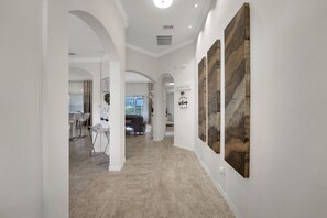 A hallway with a modern interior, featuring a dining area with bar stools, a seating area with a sofa, and artwork on the walls. - Family Escape - Pool Games Dog-friendly (Davenport)