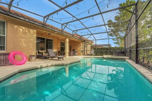 A swimming pool with a glass enclosure, lounge chairs, and a pink inflatable ring. - Family Escape - Pool Games Dog-friendly (Davenport)