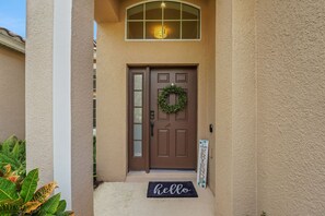 A brown front door with a wreath, a 'hello' mat, and a 'welcome' sign. - Family Escape - Pool Games Dog-friendly (Davenport)