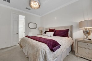 A bedroom with a large bed, a nightstand, a mirror, and a chandelier. - Family Escape - Pool Games Dog-friendly (Davenport)