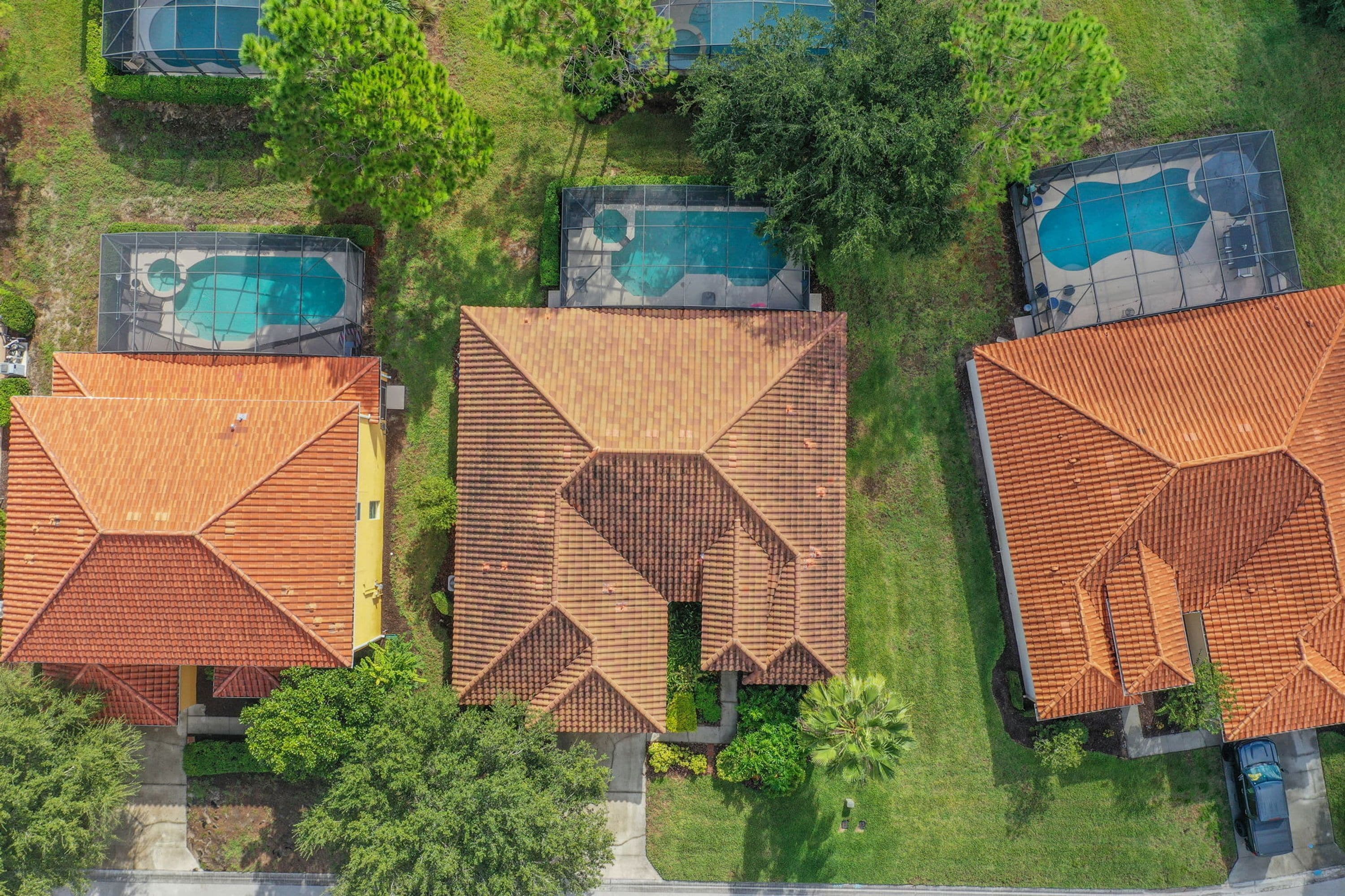 A residential area with multiple houses, each featuring a distinct roof design and a swimming pool.