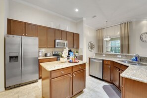 A modern kitchen with wooden cabinets, stainless steel appliances, a granite countertop, and a built-in dishwasher. - Family Escape - Pool Games Dog-friendly (Davenport)