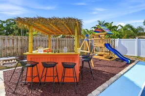 A children's play area with a slide, a small playhouse, and a bar area with stools. - Sleeps 14 Sport Court Tiki Bar Heated Pool (Bradenton)