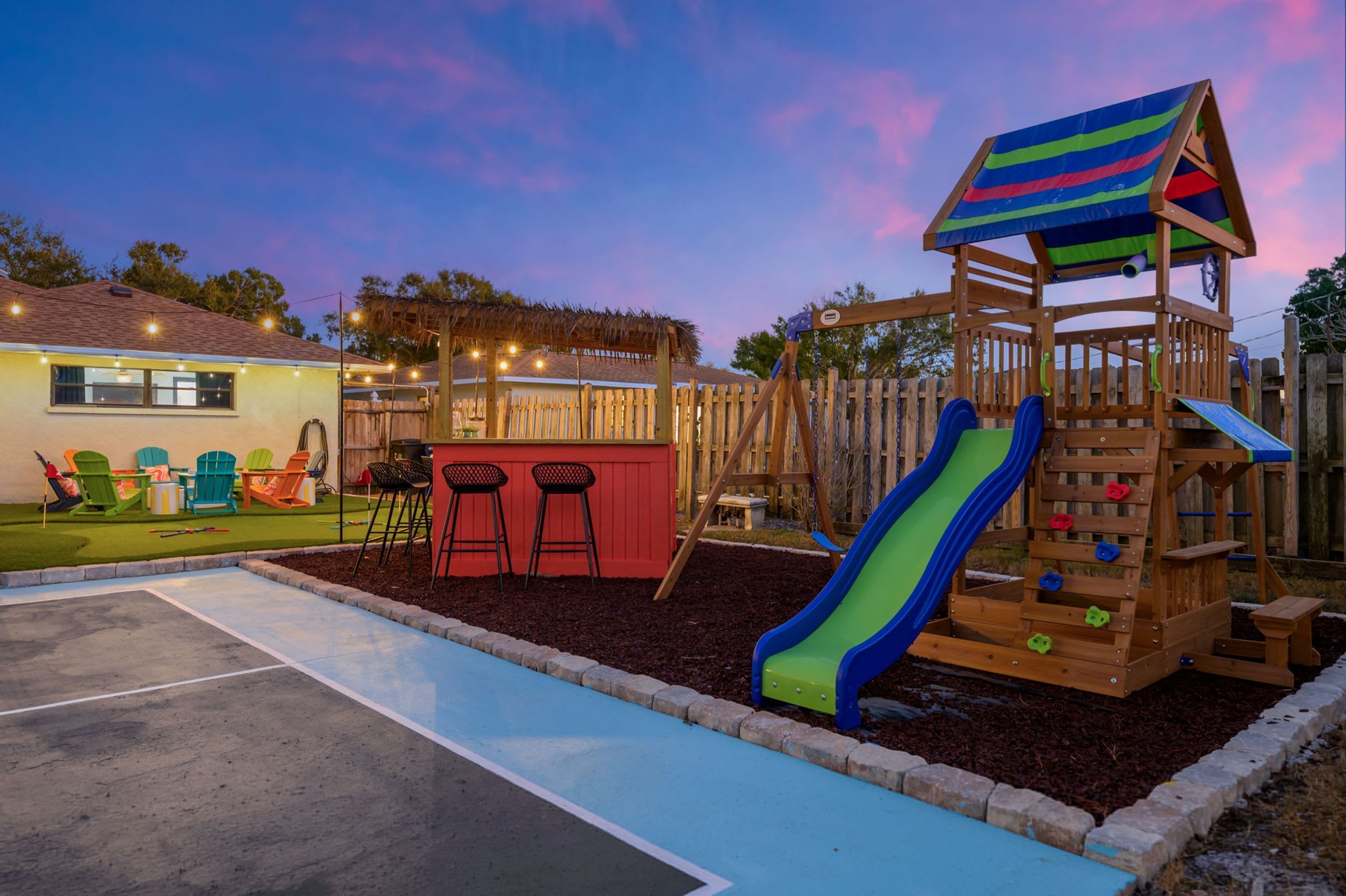 Un espace de jeux pour enfants avec un toboggan, une structure d’escalade et un coin salon.