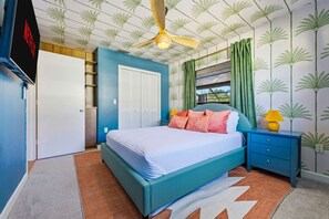 Ein Schlafzimmer mit einem Bett, einem Nachttisch, einem Kleiderschrank und einem Deckenventilator.