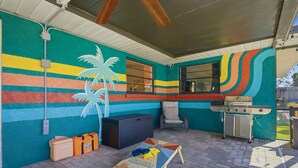 Un'area patio esterna con un murale colorato, un barbecue e una zona salotto.