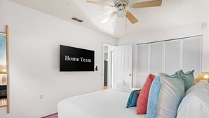 A bedroom with a bed, pillows, a television, a ceiling fan, and a door. - Ultimate Family Retreat - Pool - Games - Hot Tub (Seminole)