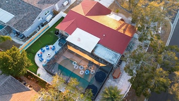 Una propiedad residencial con piscina, mobiliario exterior y un edificio de techo rojo.