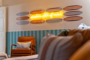 Una habitación con un aplique de pared que deletrea 'sunshine state of mind', rodeado de formas ovaladas de madera.