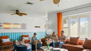 A modern living room with a ceiling fan, a wall-mounted light fixture, and a large window with curtains. - Ultimate Family Retreat - Pool - Games - Hot Tub (Seminole)
