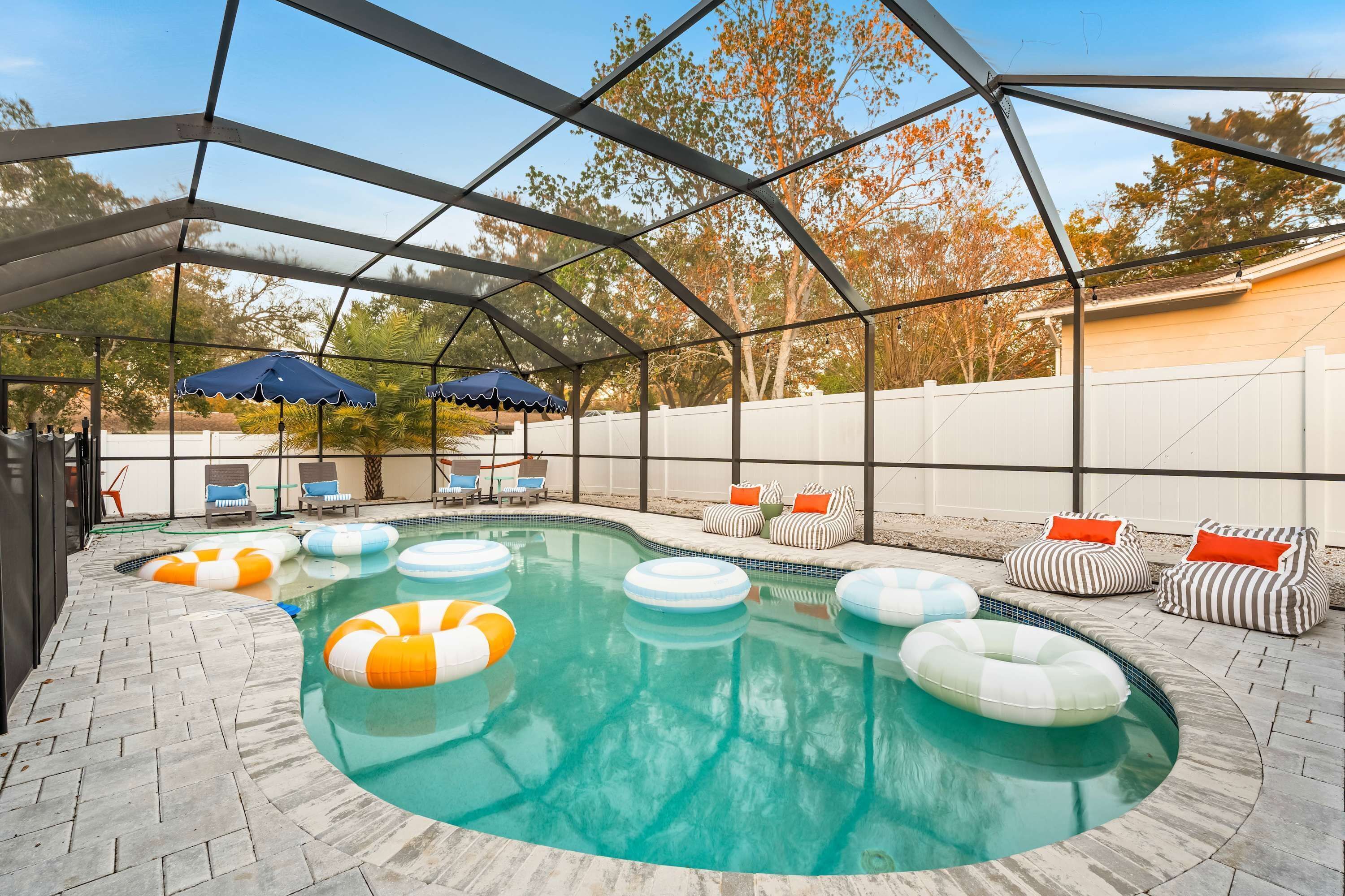 A covered outdoor swimming pool with lounge chairs and umbrellas.