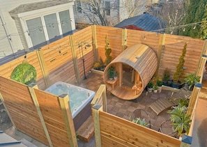 Eine Holzterrasse mit Whirlpool, Sauna und Topfpflanzen.