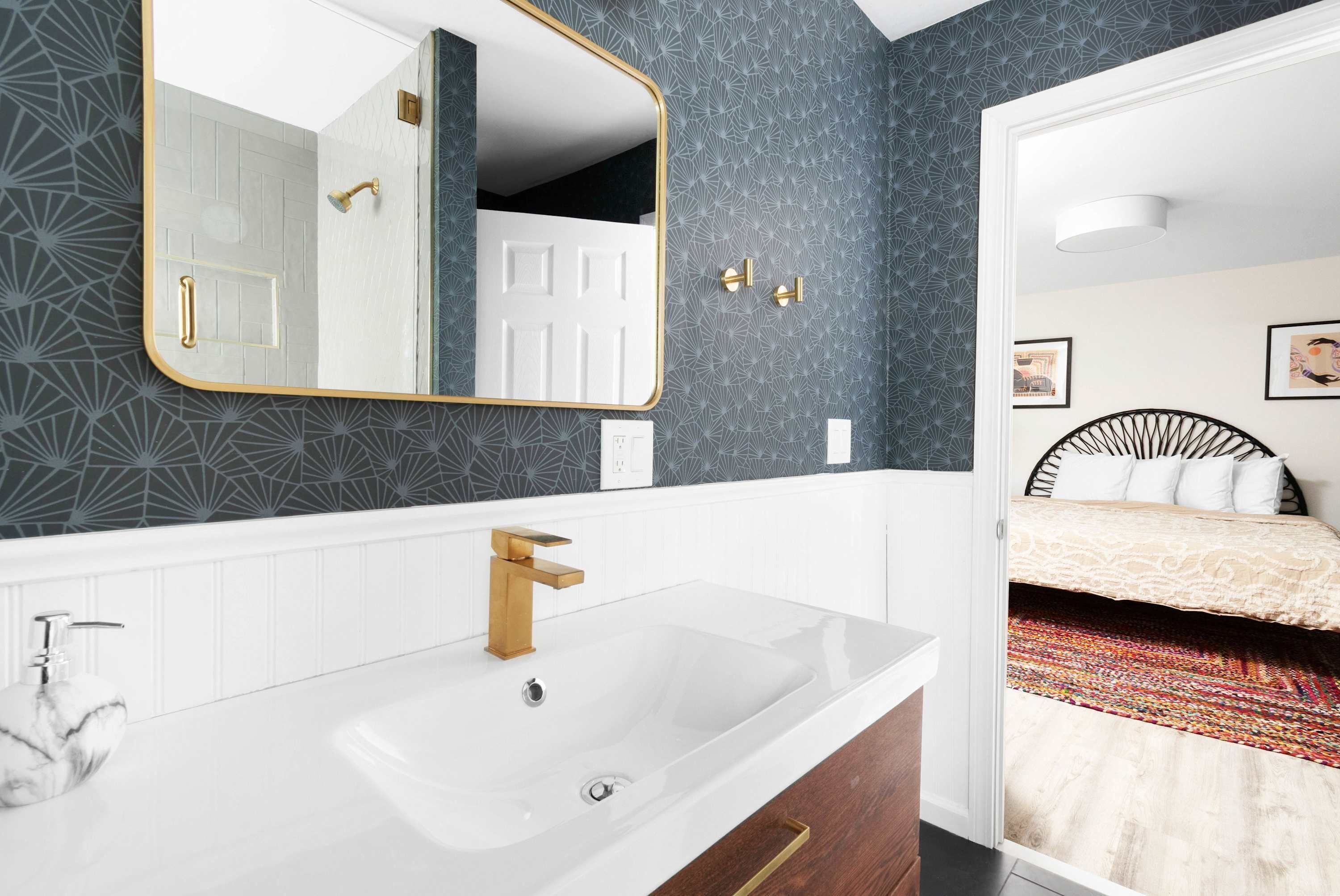 Une salle de bain avec un lavabo blanc, un robinet doré et un miroir avec un cadre doré.