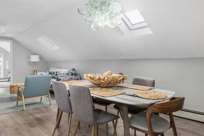 Ein Essbereich mit hoher Decke, einer Kristallleuchtre und einem Tisch, der mit Platzsets und einer Tischdekoration gedeckt ist.