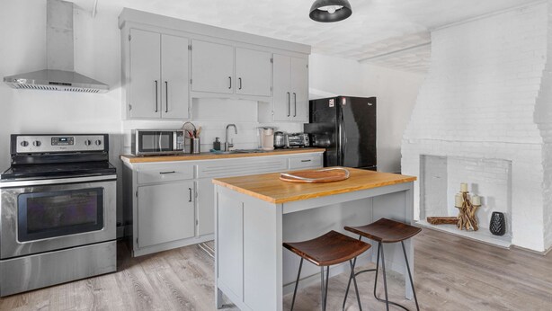 A modern kitchen with stainless steel appliances, a wooden island, and bar stools. - Private Retreat Buyout Sleeps 16 Spa 4 Units (Warren)
