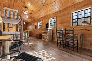 A log cabin interior with a dining area, a fireplace, and a large window. - River Lodge Kayaks Mins to Blue Ridge River (Epworth)