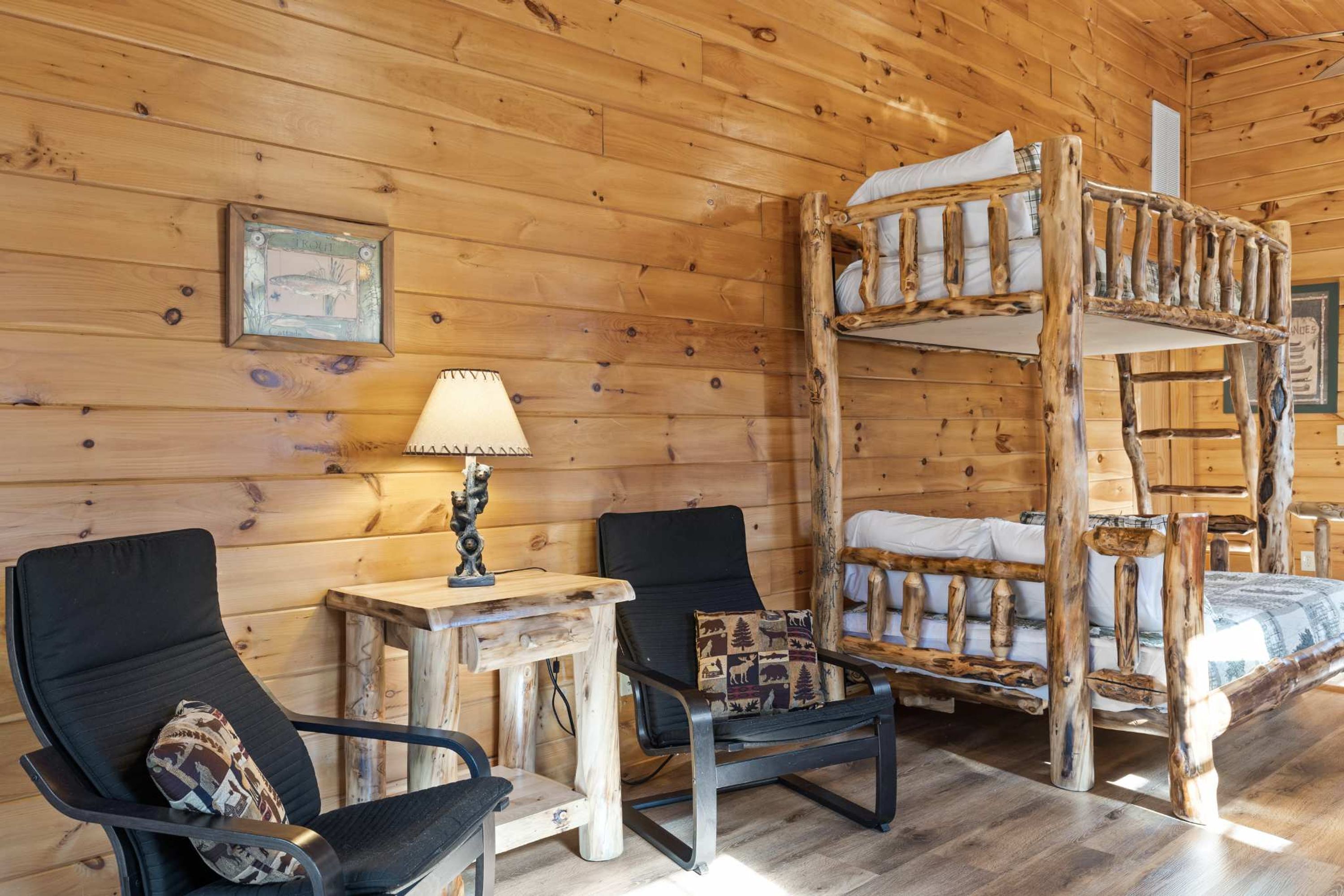 Interno di una cabina con un letto a castello, due sedie, un tavolino e una lampada.