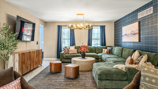 A modern living room with a sectional sofa, a coffee table, and a television mounted on the wall. - Epic Poconos Pad Pool Hot Tub Gym Golf Sim (East Stroudsburg)