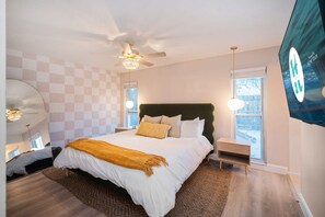 Ein Schlafzimmer mit einem großen Bett, einem Deckenventilator, einem Fernseher und einem Fenster mit Blick.