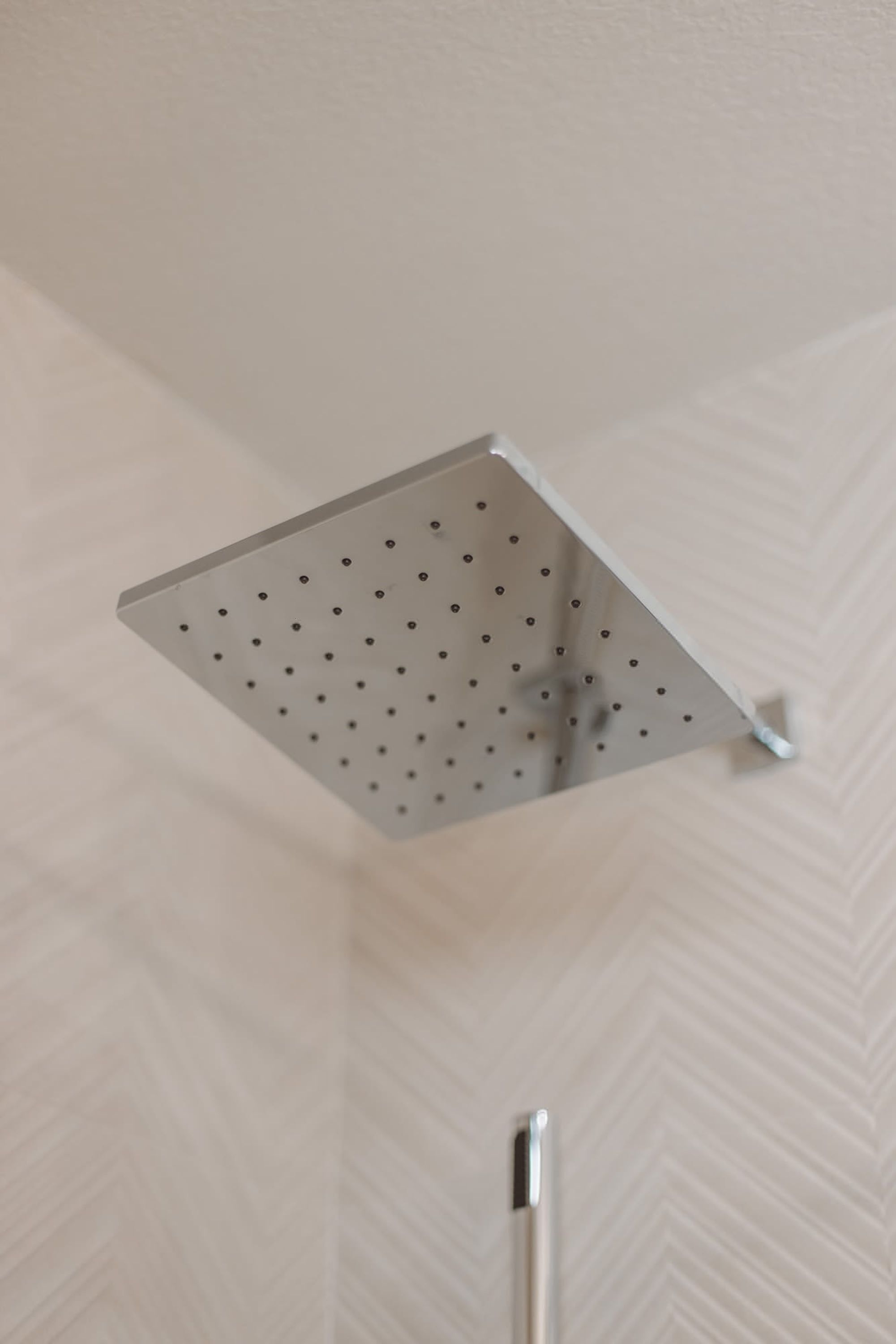 A showerhead with a square design and multiple holes.