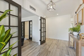 A hallway with a sign indicating a game room, wooden flooring, and a hanging light fixture. - Sonoran Sunset Retreat Pool Games (Scottsdale)