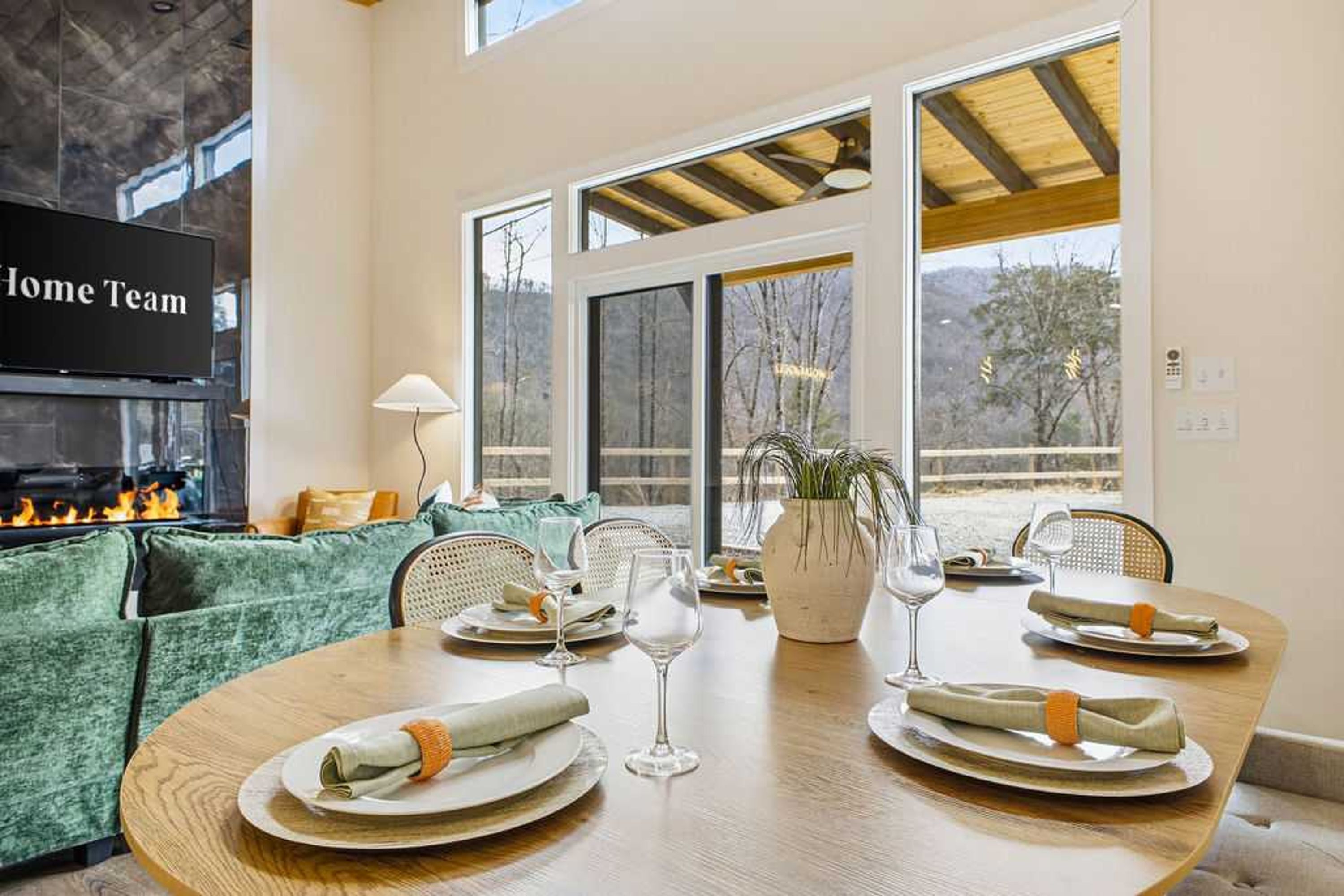 A dining area with a wooden table set for four, a sofa, and a fireplace.