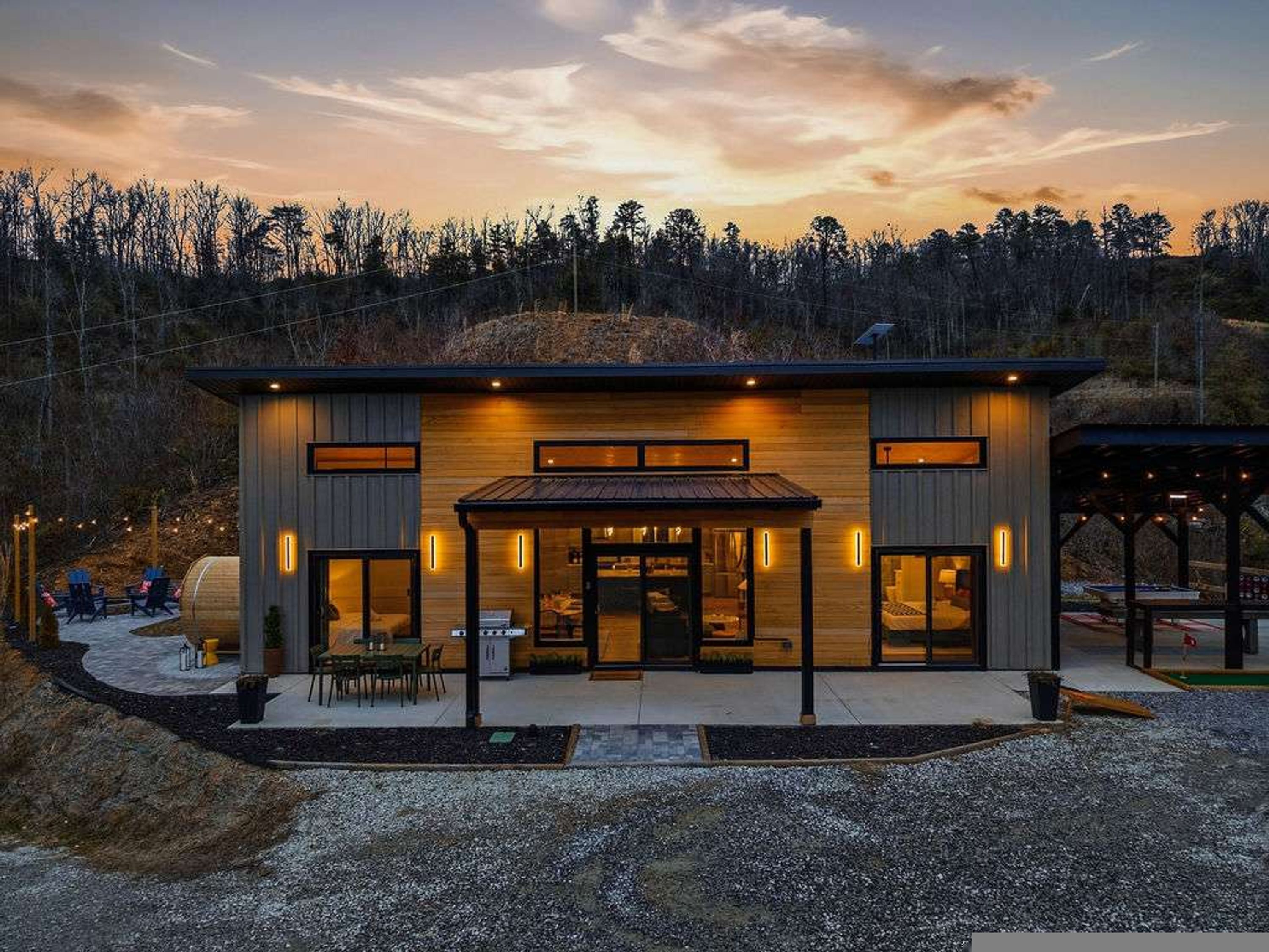 A modern two-story building with a flat roof, large windows, and a covered patio area.