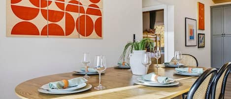 Comedor con una mesa redonda dispuesta para cuatro personas, rodeada de sillas con asientos de mimbre.