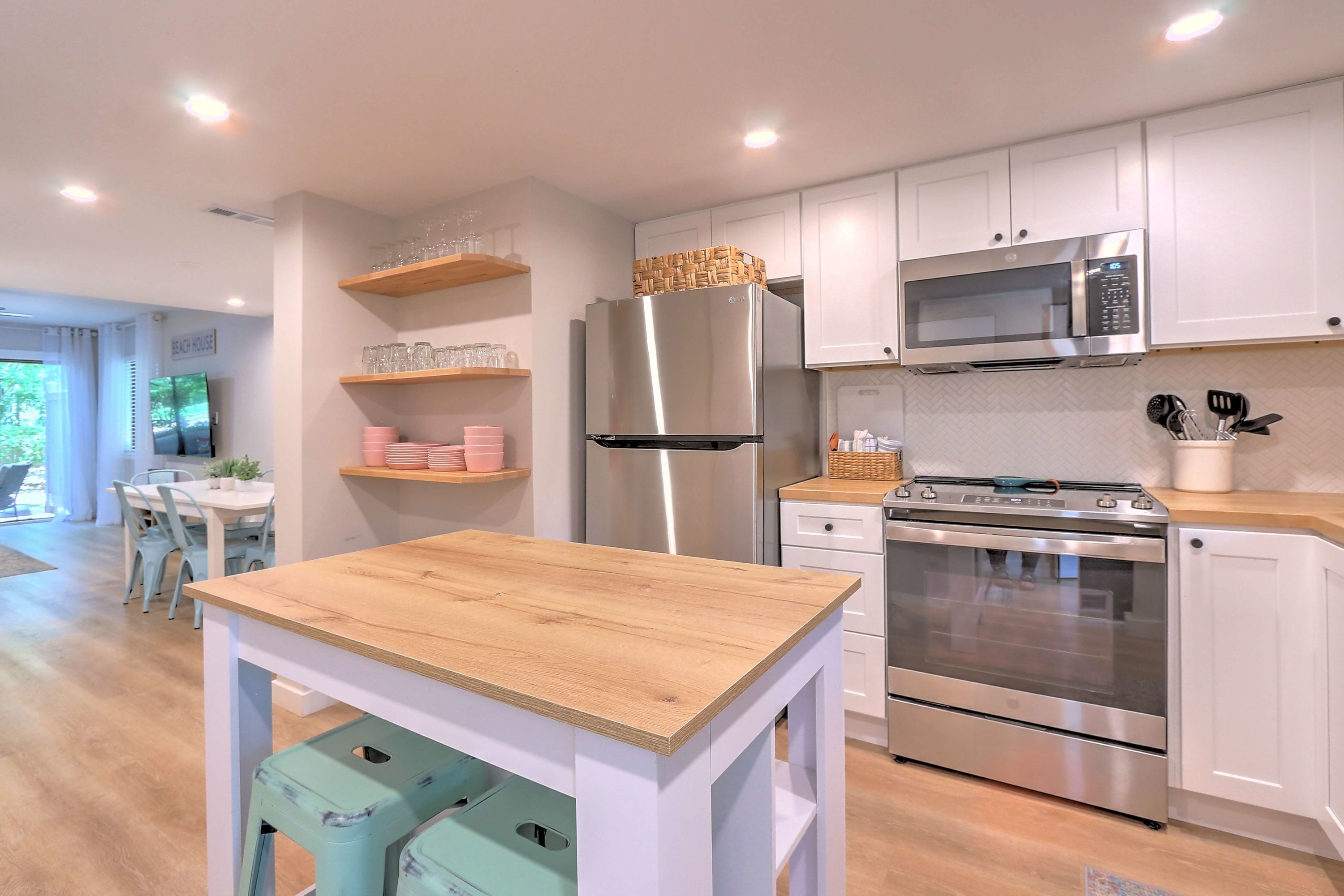 A modern kitchen with white cabinetry, stainless steel appliances, and a wooden table.