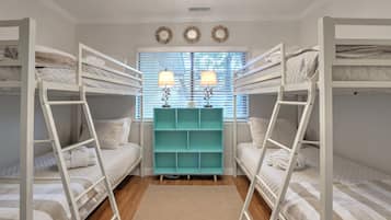 Une chambre avec un lit superposé, un meuble de rangement turquoise et deux lampes fixées au mur.