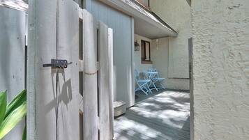 Una puerta de madera que da a un porche cubierto con mesa y sillas.