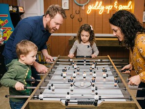 A family playing foosball with a neon sign in the background. - Private Resort 4 Baths Near Pearl (San Antonio)