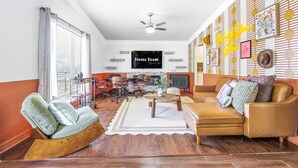 Een woonkamer met een bank, fauteuils, een salontafel, een televisie en een open haard.