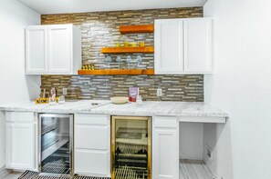 A compact kitchen with white cabinets, a stone backsplash, and a built-in wine cooler. - Private Resort 4 Baths Near Pearl (San Antonio)