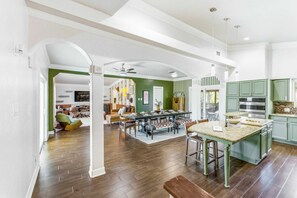 A spacious kitchen with a central island, green cabinets, and a dining area with a large table. - Private Resort 4 Baths Near Pearl (San Antonio)