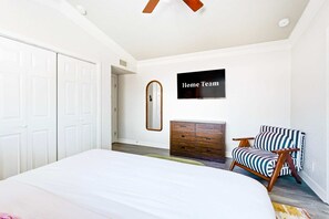 A bedroom with a bed, a dresser, a chair, and a wall-mounted TV. - Private Resort 4 Baths Near Pearl (San Antonio)