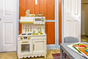 A children's play kitchen with a microwave, stove, and sink, set against a wall with a red panel. - Private Resort 4 Baths Near Pearl (San Antonio)