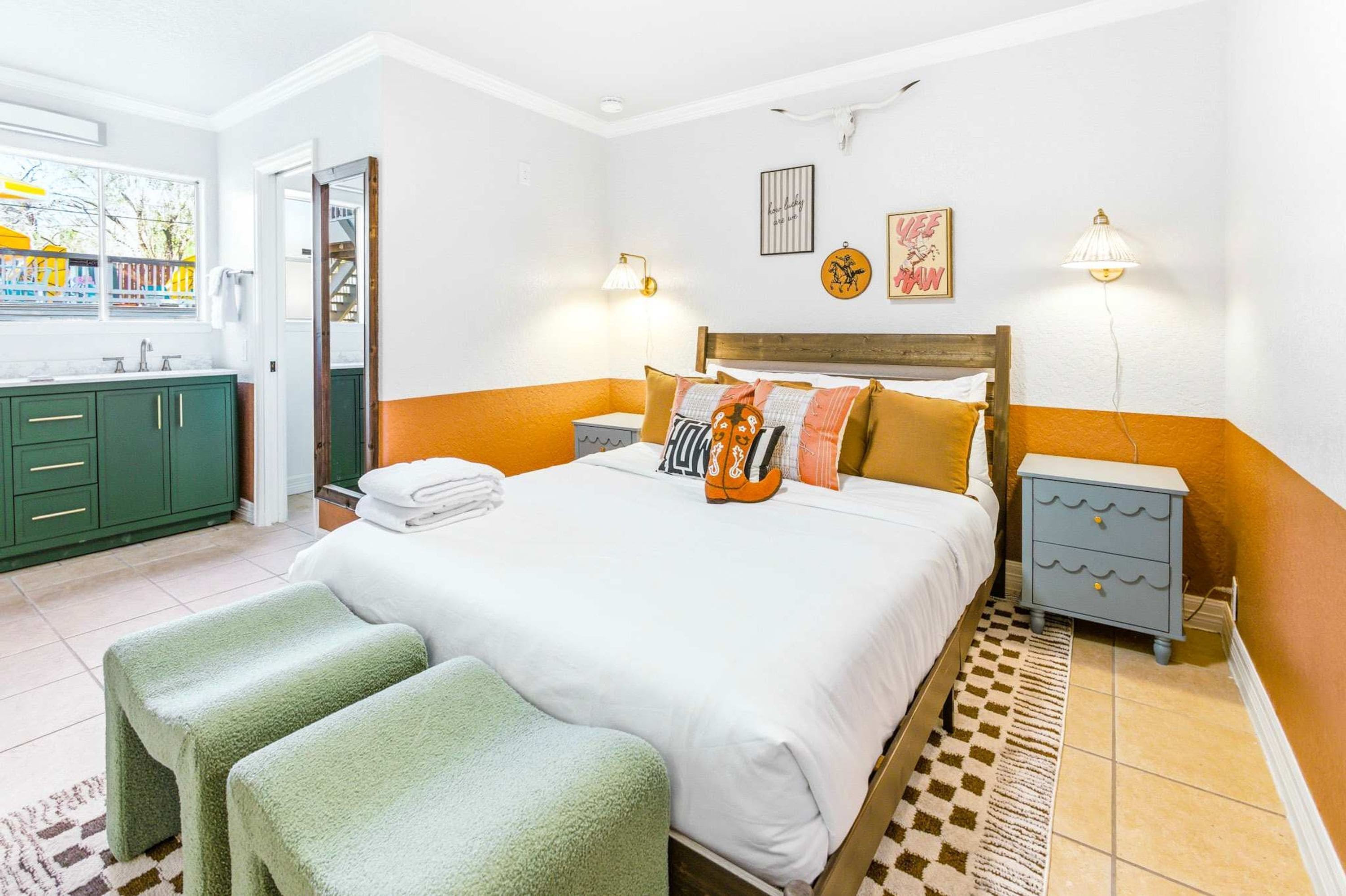 Ein Hotelzimmer mit Bett, Nachttisch, Kommode und Fenster mit Blick.