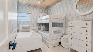 A bedroom with bunk beds, a dresser, and a window. - Beachfront Bliss - Outdoor Pool - Sleeps 6 (Belleair Beach)