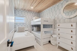 A bedroom with bunk beds, a dresser, and a window. - Beachfront Bliss - Outdoor Pool - Sleeps 6 (Belleair Beach)