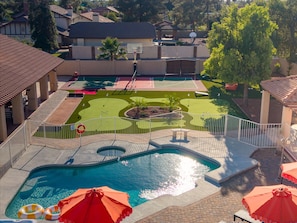 A swimming pool with a deck, surrounded by a fence, and a basketball court in the background. - Paradise Lane Pool - Hot Tub - Sports Court (Phoenix)