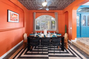 Een eethoek met een tafel voor vier personen, een plafondventilator en een raam met gordijnen.