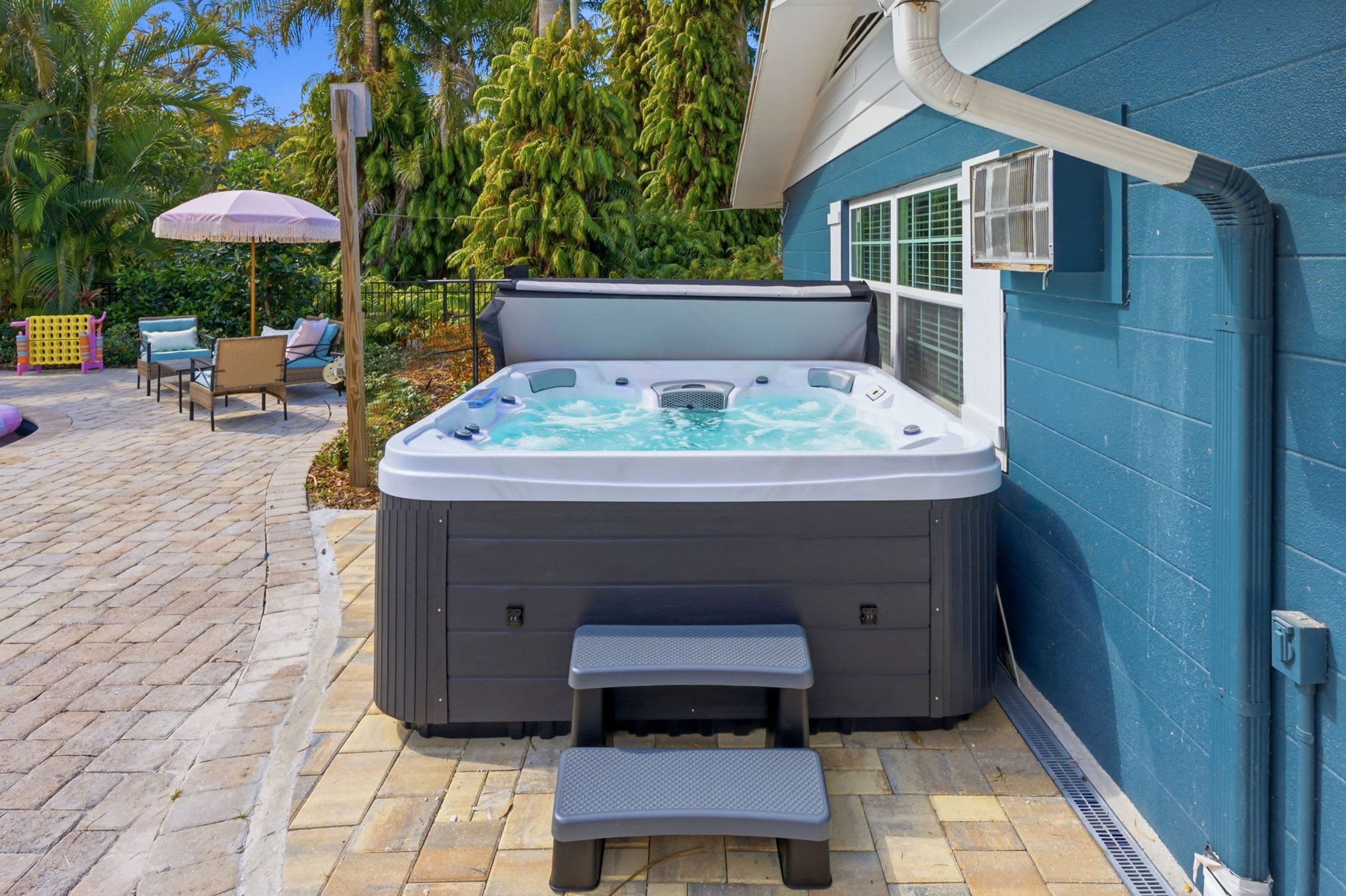 Een hottub met een opstapje ervoor, omringd door een terras met buitenmeubilair.