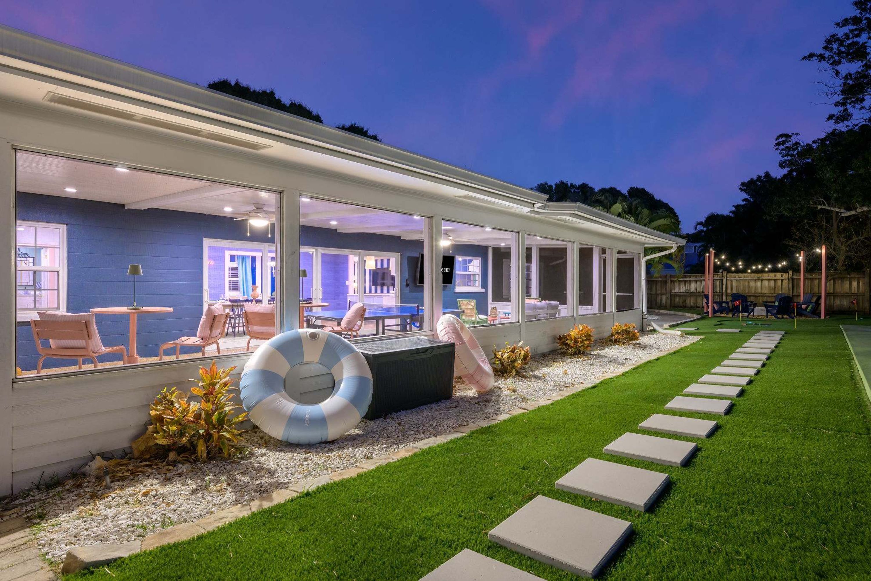 A covered outdoor seating area with a pool table, chairs, and a life ring.