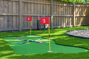 A miniature golf course with numbered flags and golf balls on artificial grass. - Bradenton Beach Club - Poolside Estate Bunkroom (Bradenton)
