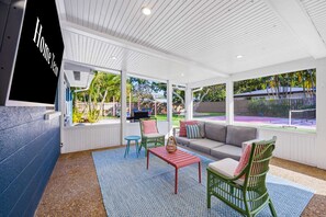 Un espacio de estar techado al aire libre con vista a la piscina, un sofá y dos sillas.