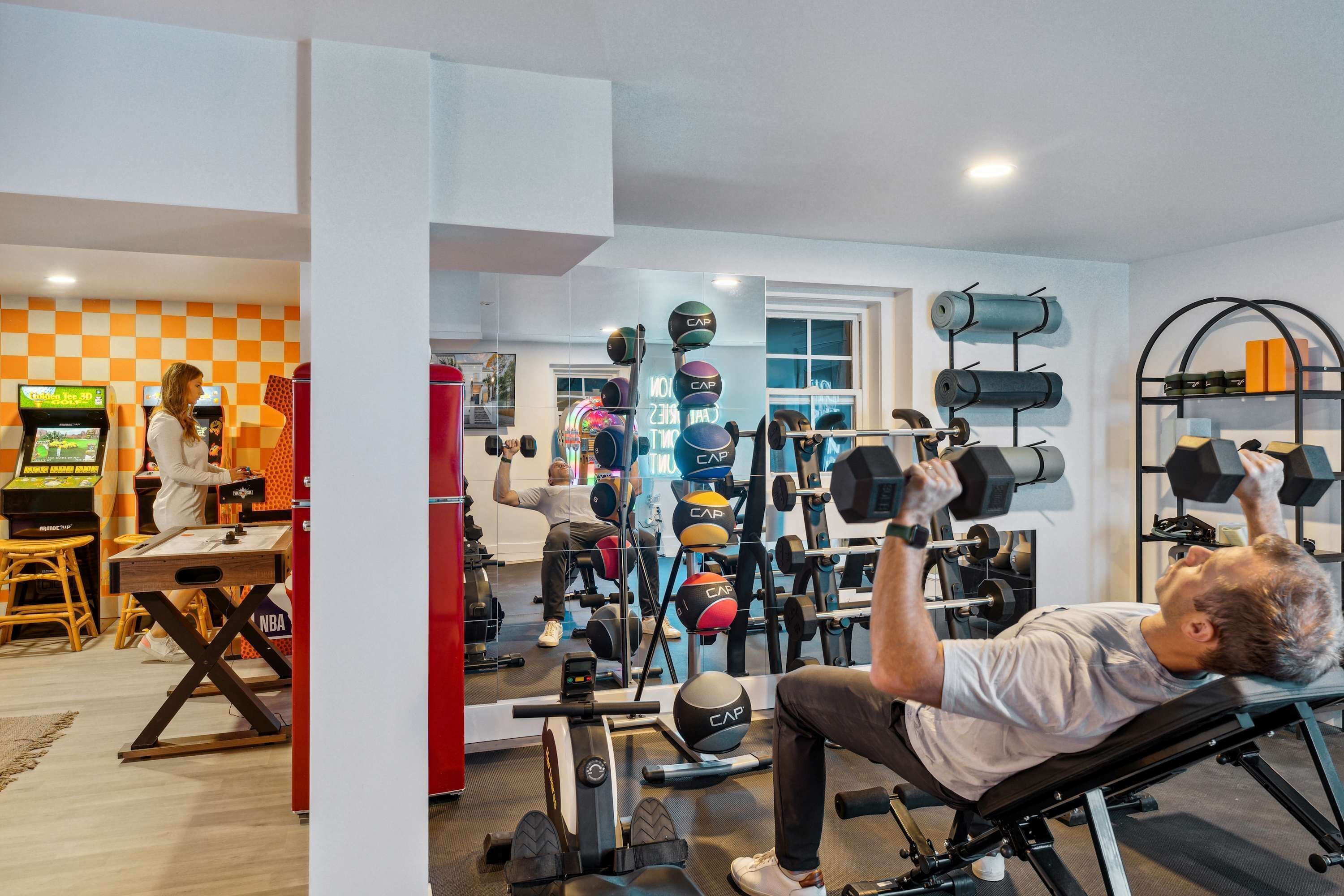 A home gym with exercise equipment, a gaming console, and a checkered wall.