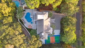 Eine Luftaufnahme eines Wohngebiets mit Swimmingpool, Sitzbereich im Freien und Tennisplatz.
